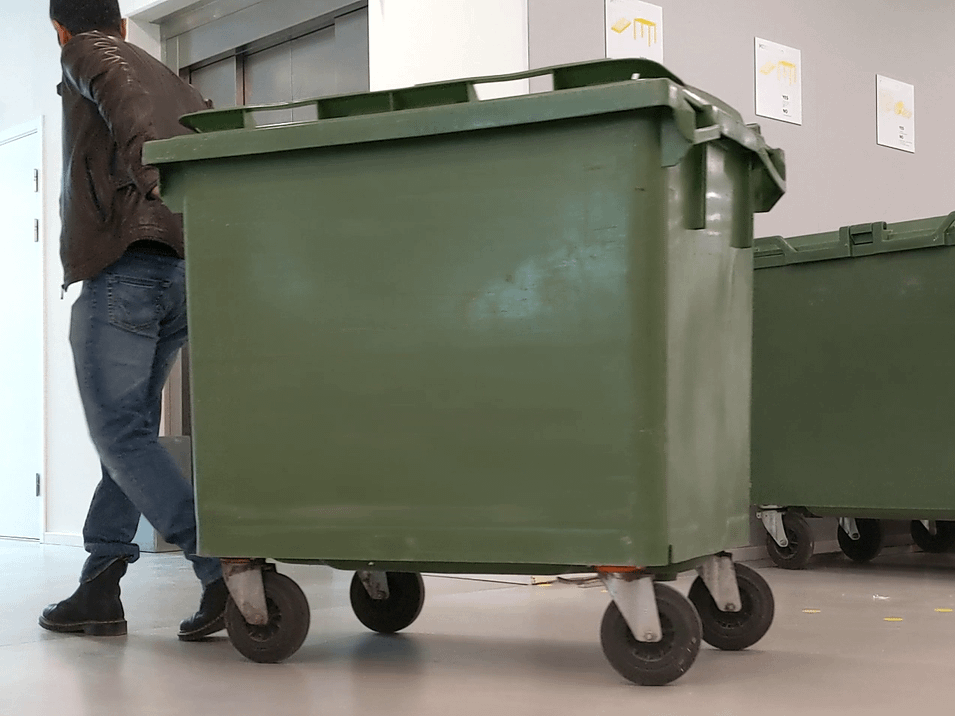 Person walking a waste container in a building
